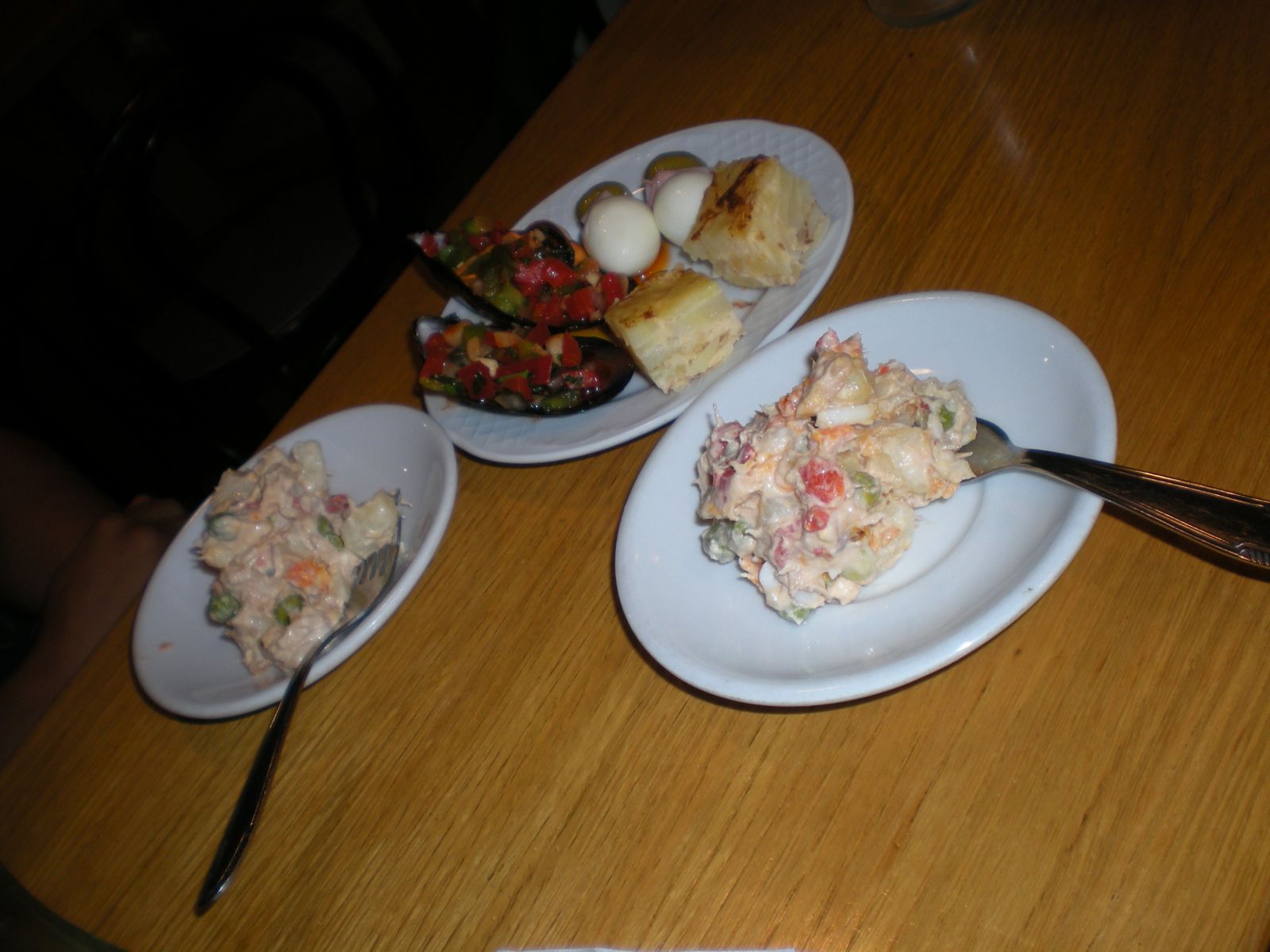 Tapas de ensaladilla, con tortilla, mejillones y huevos de codorniz en el plato de atrás